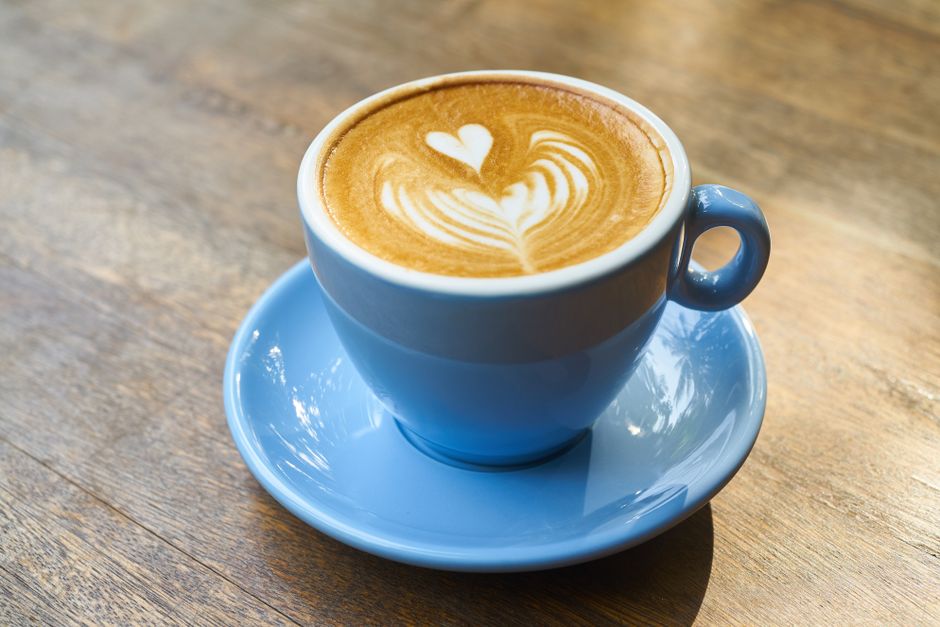 Šálek cappuccina s latte art na dřevěném stole v kavárně Kávový Koutek